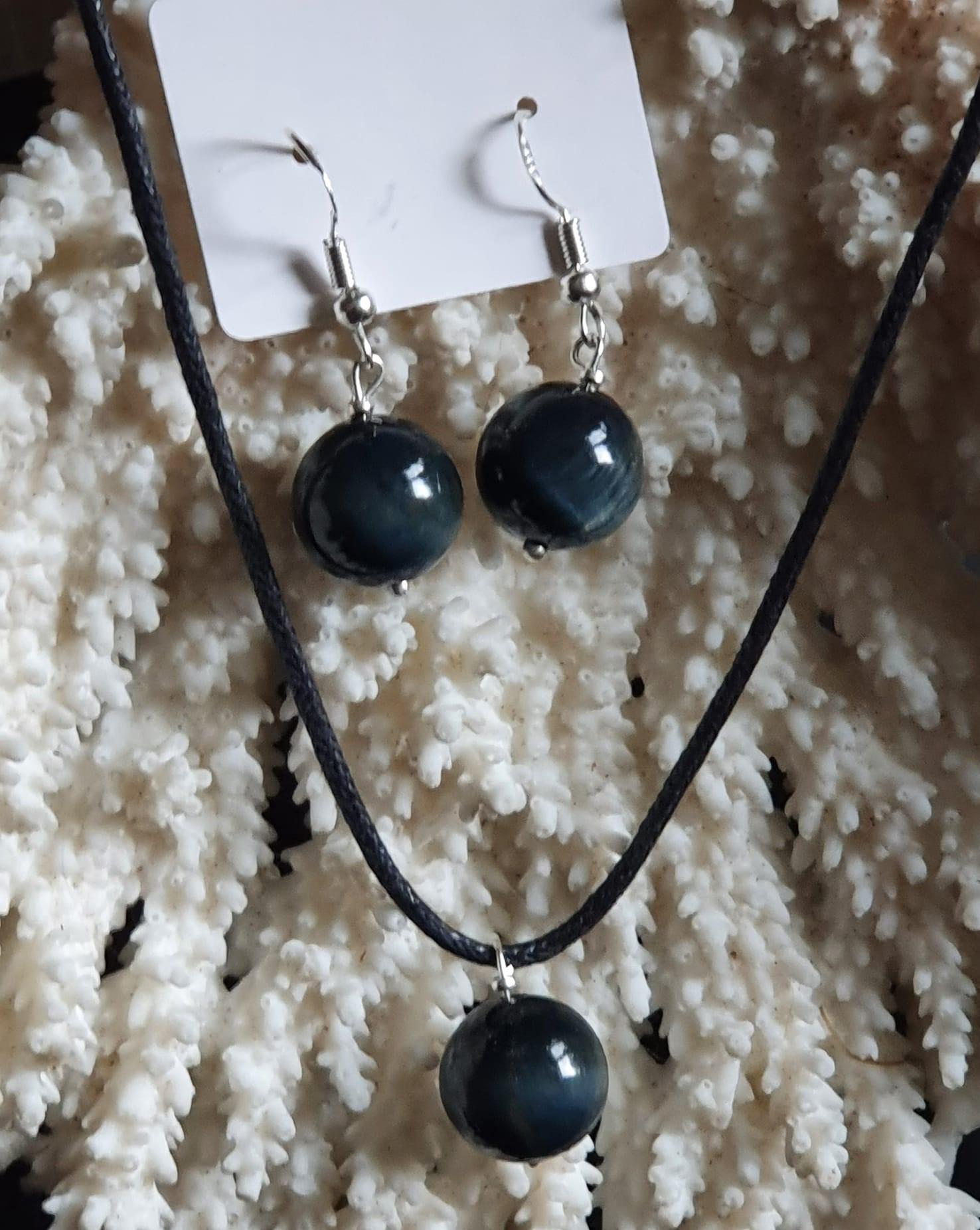 La parure composée de boucles d'oreilles et d'un pendentif en Œil de faucon attire immédiatement l'œil par son élégance et son originalité. En effet, cette combinaison de bijoux met en valeur la beauté unique de la pierre, qui se caractérise par ses nuances de bleu et de gris. De plus, l'Œil de faucon est souvent associé à des propriétés protectrices et apaisantes, ce qui ajoute une dimension spirituelle à cette parure. Ainsi, cet ensemble de bijoux allie esthétique et symbolisme, séduisant ceux qui souhaitent exprimer leur style tout en bénéficiant des vertus de la pierre.