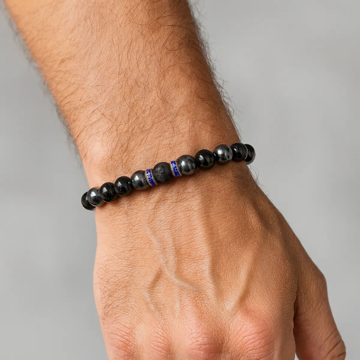 Bracelet de protection en obsidienne argentée, hématite et pierre de lave porté au poignet d’un homme.