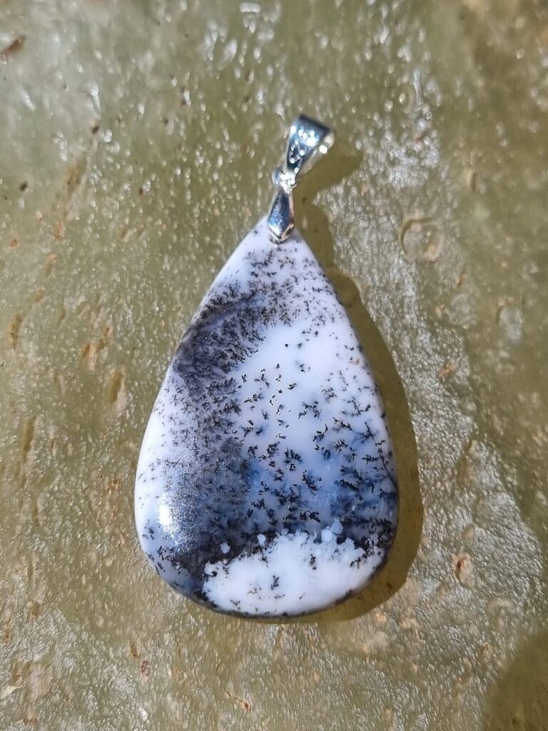 Découvrez notre élégant pendentif en agate dendritique/Merlinite, qui allie beauté naturelle et énergie positive. En effet, ce bijou unique se distingue par ses motifs fascinants et ses propriétés protectrices. De plus, l'agate dendritique est réputée pour favoriser la croissance personnelle, elle stimule l'intuition. N'attendez plus pour enrichir votre collection avec ce pendentif exceptionnel et profiter de ses bienfaits !