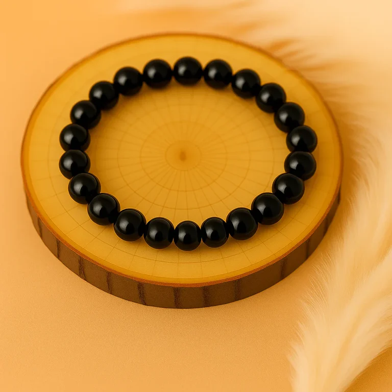 Bracelet en tourmaline noire naturelle posé sur un support en bois, symbole de protection et d’ancrage.