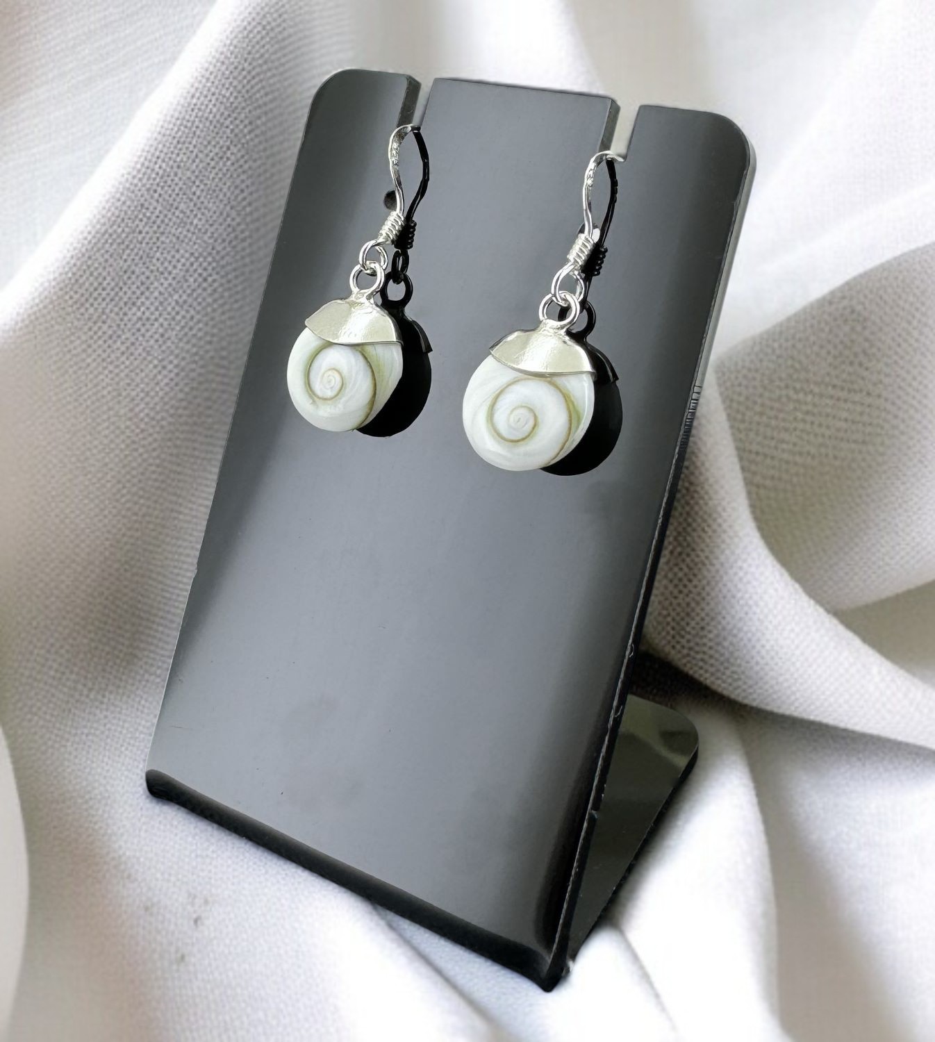 Apportez élégance et protection avec ces boucles d’oreilles Œil de Sainte Lucie. Ce bijou coquillage méditerranéen porte chance, éloigne le mauvais œil et séduit par ses nuances naturelles blanches et orangées. Un accessoire raffiné et chargé d’énergie positive.