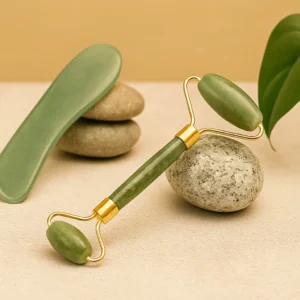 Roller de jade posé sur des pierres naturelles avec feuille verte, accessoire de massage facial zen.