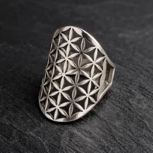 Bague en argent ajourée avec motif géométrique « Fleur de Vie », photographiée en gros plan sur un fond ardoise noir.