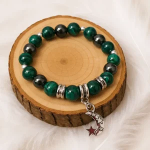 Bracelet anti-douleur en malachite et hématite avec pendentif lune présenté sur rondin en bois