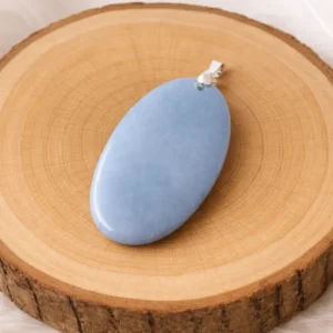Pendentif Angélite pierre naturelle posé sur rondin de bois – bijou apaisant