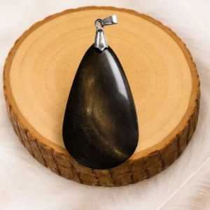 pendentif en obsidienne dorée naturelle avec bélière en argent sur rondin de bois