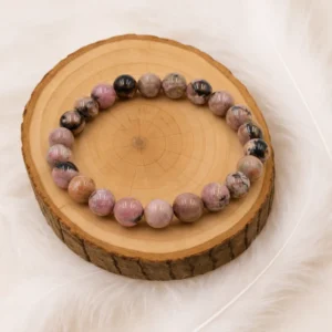 Bracelet rhodonite en pierre naturelle posé sur un rondin de bois