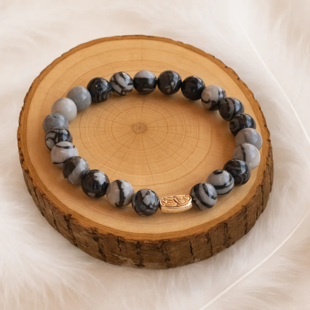 Bracelet en jaspe toile d’araignée naturel posé sur un rondin en bois
