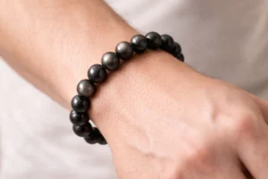 Bracelet en obsidienne argentée 8mm porté au poignet, perles noires aux reflets argentés