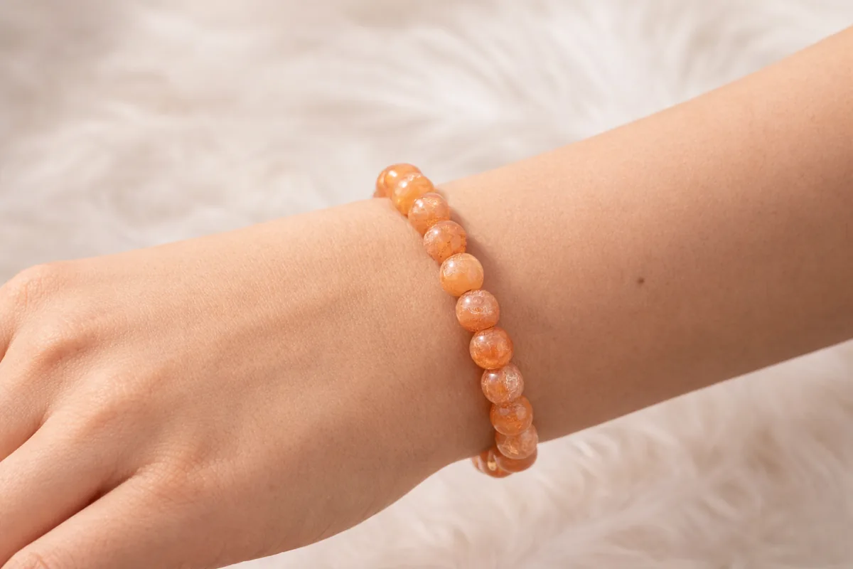 Bracelet pierre de soleil porté au poignet, perles naturelles orange lumineuses