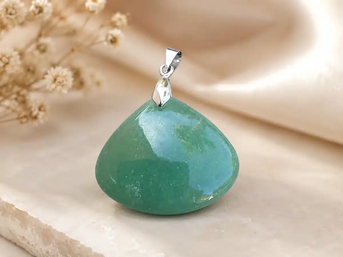 Pendentif en Aventurine verte naturelle posé sur un support beige avec bélière argentée