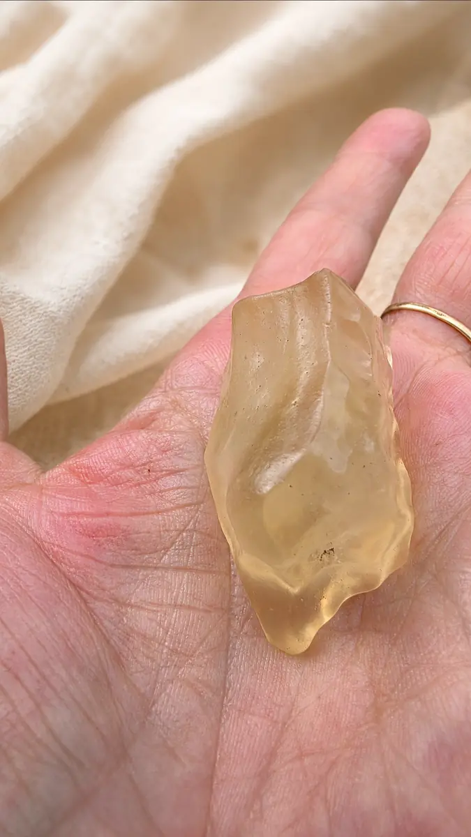 Tectite dorée en verre libyque naturel présentée dans une main