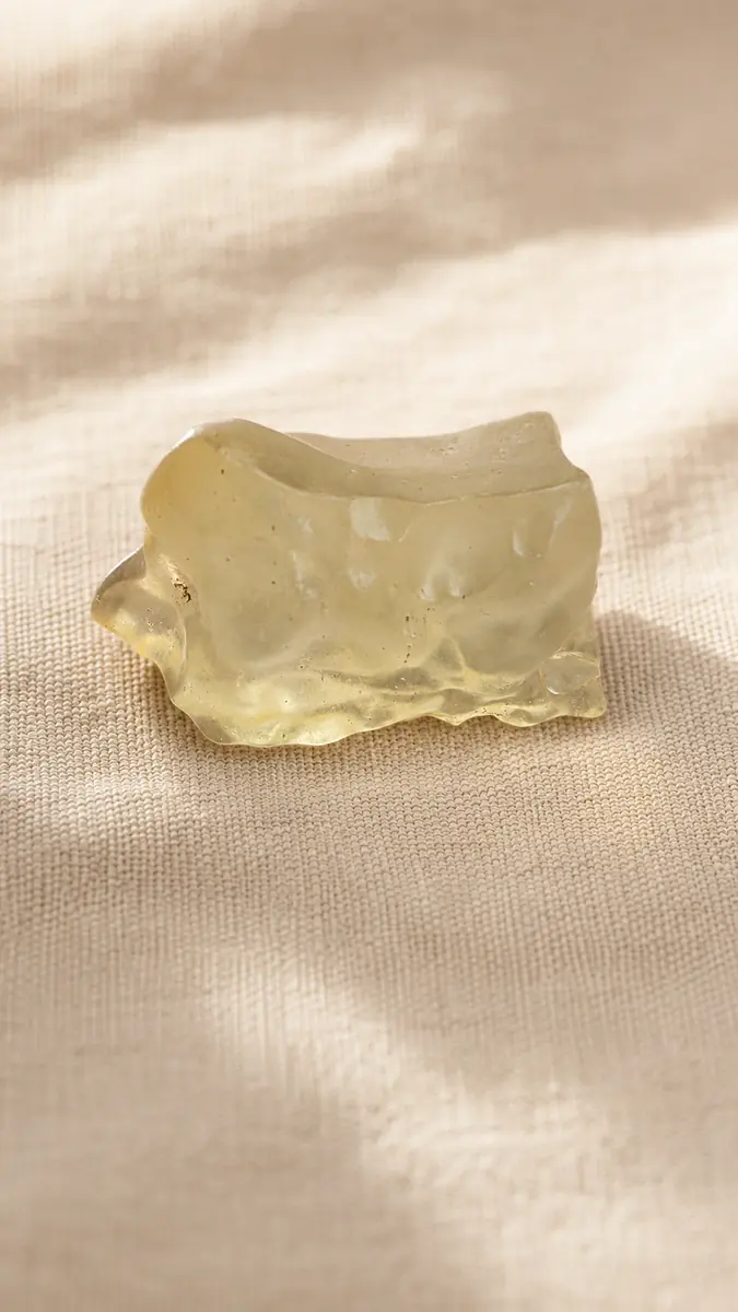 Vue de profil d’une tectite dorée brute en verre libyque naturel