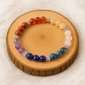 Bracelet 7 chakras et pierres naturelles présenté sur un rondin de bois avec perles colorées