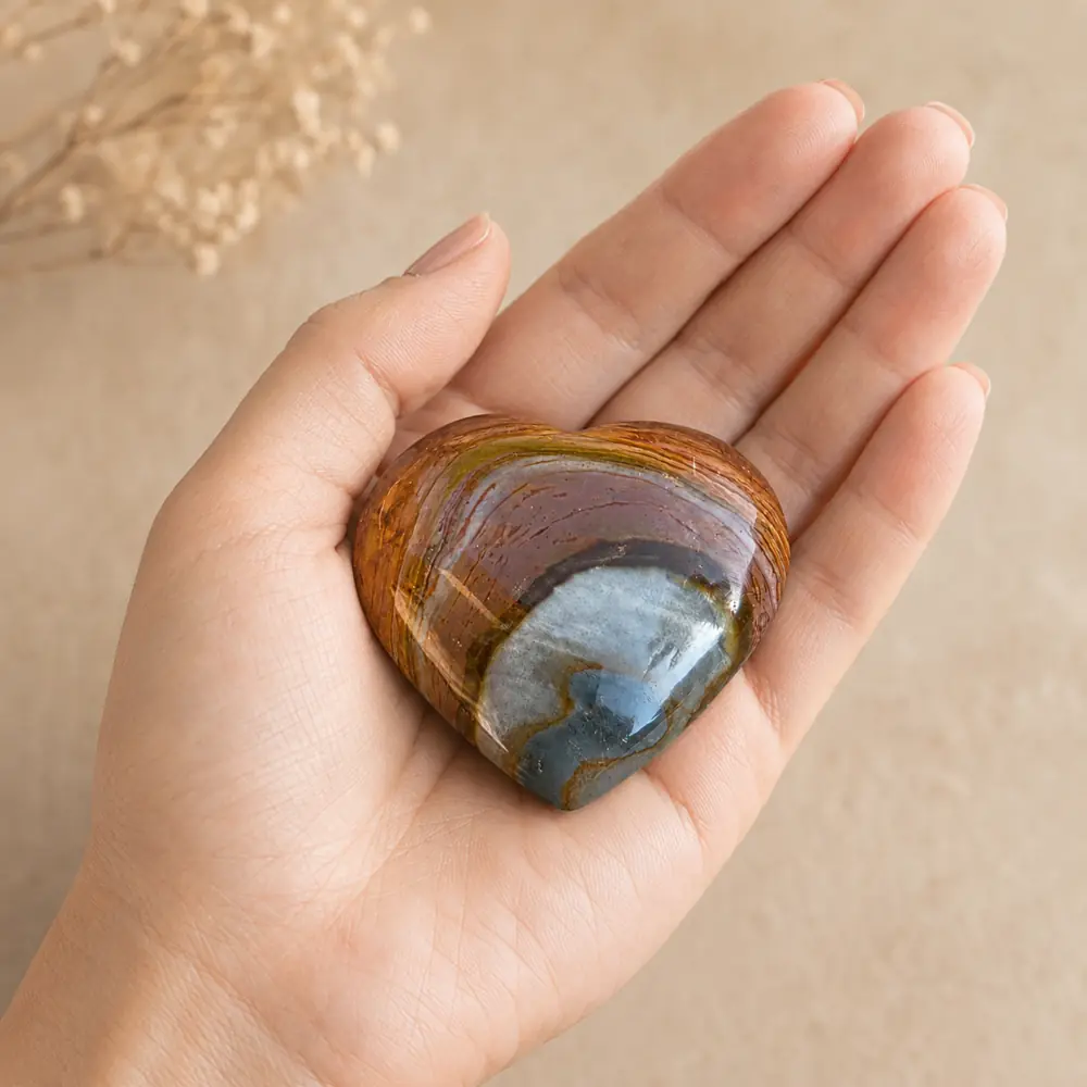 Cœur en jaspe polychrome de 4 × 4 cm présenté dans une main