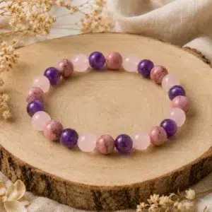 Bracelet amour de soi en rhodonite, quartz rose et améthyste posé sur un rondin de bois