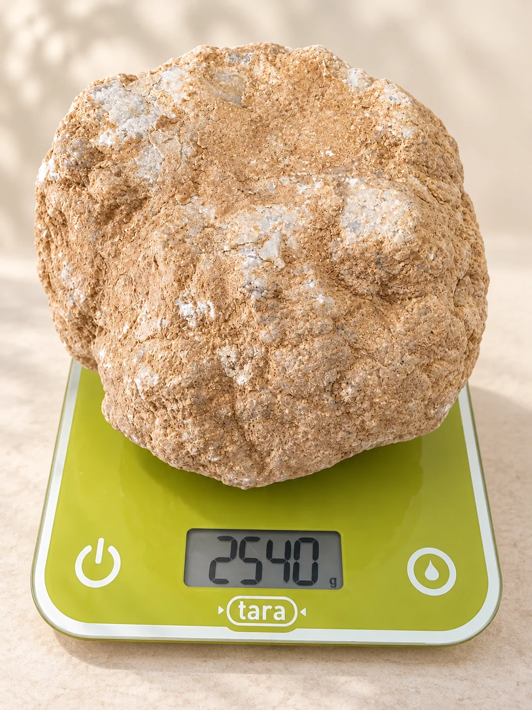 Géode quartz blanc brute pesant 2540 g sur une balance verte