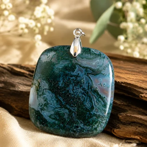 Pendentif en agate mousse carré de 30 mm présenté sur un fond naturel avec bois et fleurs blanches